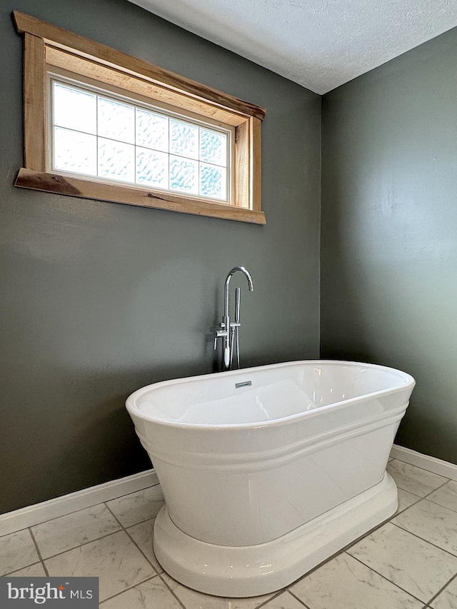 bathroom featuring plenty of natural light, a bath, and a textured ceiling