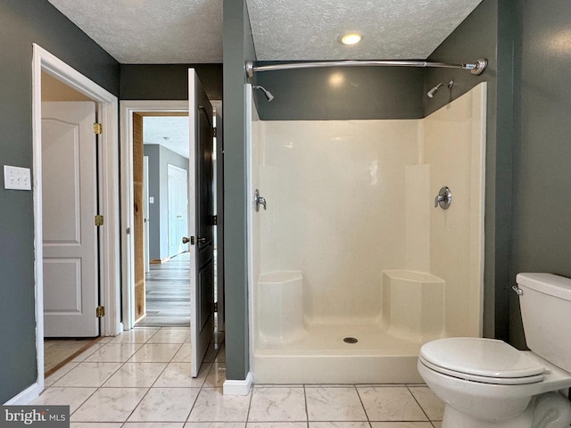 bathroom featuring walk in shower, toilet, and a textured ceiling