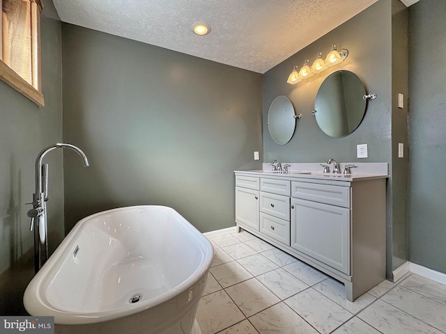 bathroom with vanity, a textured ceiling, and a tub