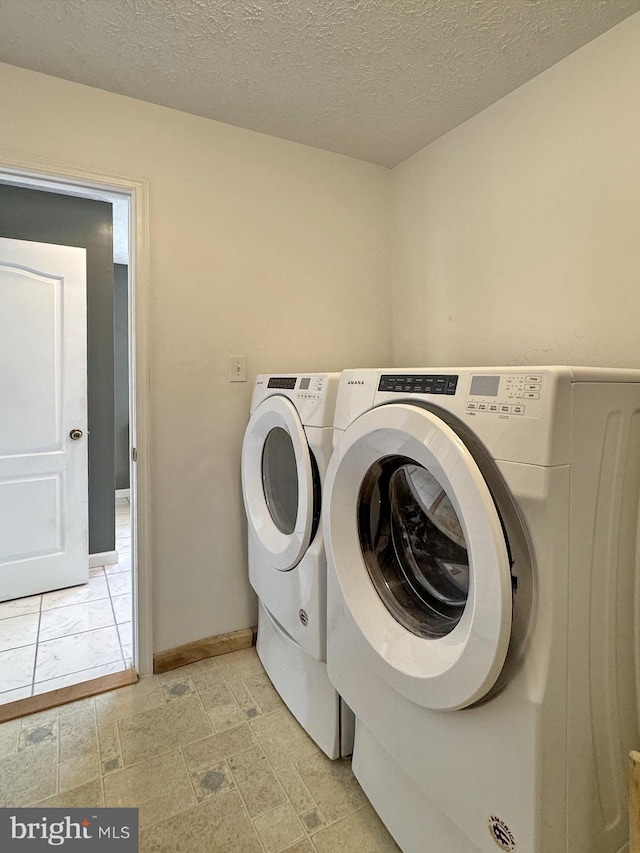 clothes washing area featuring washing machine and dryer and a textured ceiling