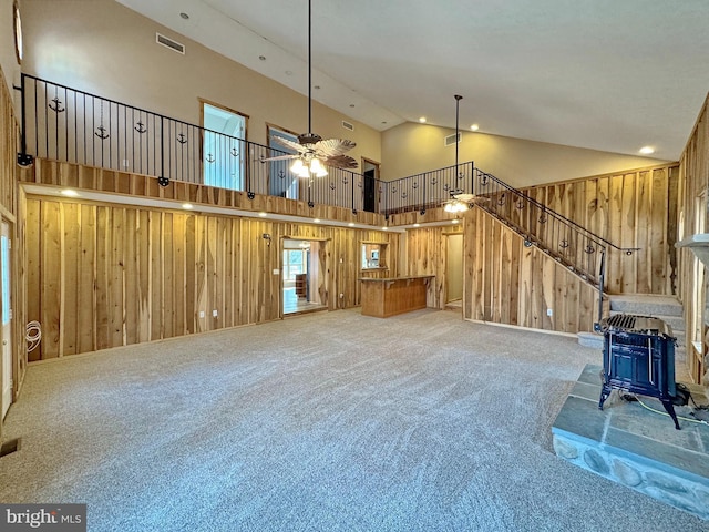 unfurnished living room featuring carpet, a wood stove, and wood walls