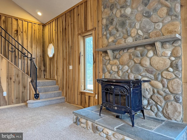 living room with lofted ceiling, a wood stove, and wood walls