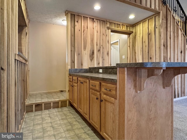 bar featuring wooden walls and a textured ceiling