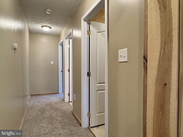 corridor featuring light colored carpet and a textured ceiling