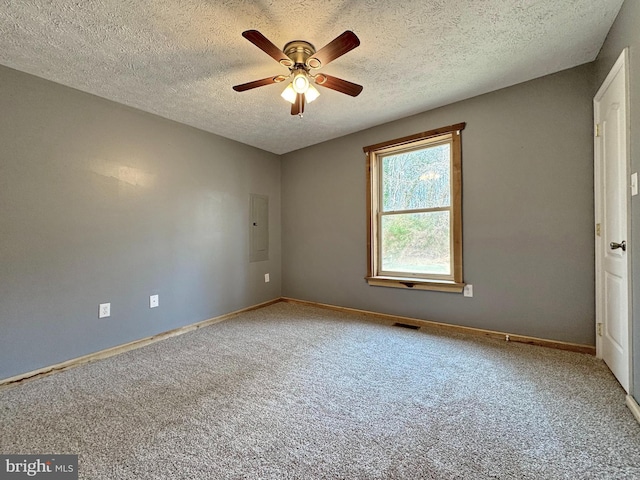 carpeted spare room with ceiling fan, electric panel, and a textured ceiling