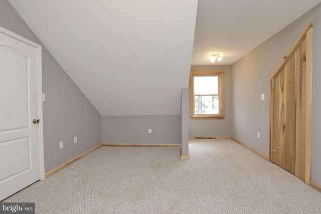 bonus room featuring vaulted ceiling and light colored carpet