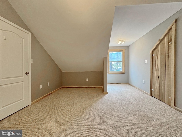 bonus room with light colored carpet and vaulted ceiling