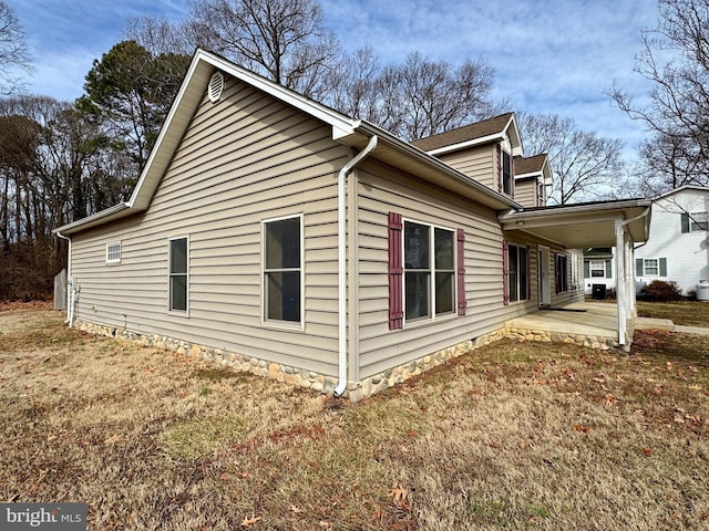 view of side of home with a yard and a patio area