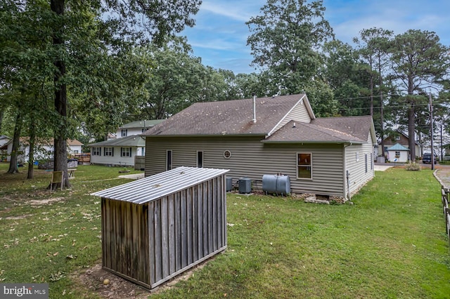 rear view of house featuring central AC, a shed, and a lawn