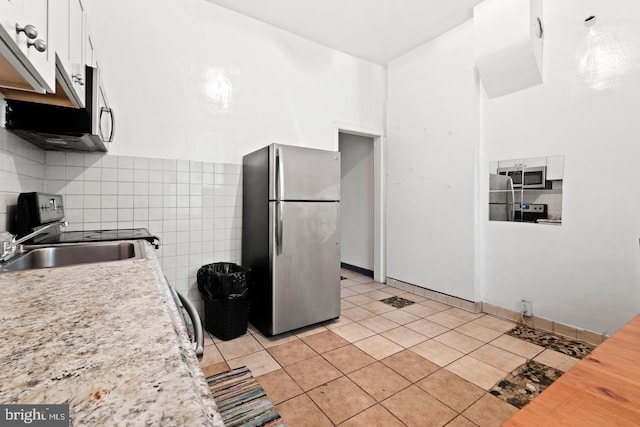 kitchen featuring light tile patterned floors, sink, backsplash, stainless steel appliances, and white cabinets