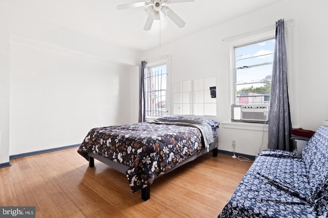 bedroom featuring cooling unit, hardwood / wood-style floors, and ceiling fan