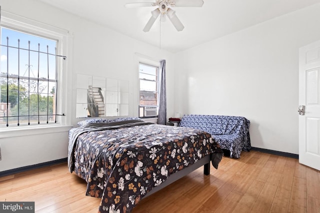 bedroom with ceiling fan, multiple windows, and light wood-type flooring