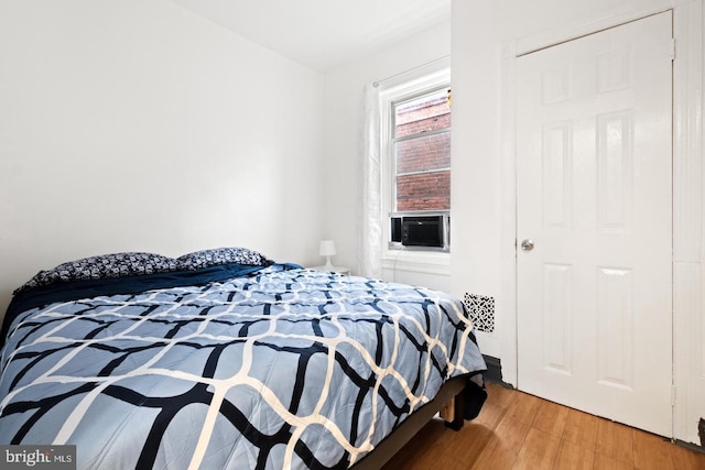 bedroom with cooling unit and wood-type flooring