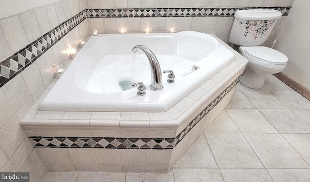 bathroom with tile patterned flooring, tiled bath, and toilet