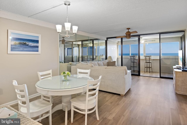 10300 Coastal Hwy Unit 104, Ocean City, MD 21842 - dining room featuring a textured ceiling, baseboards, wood finished floors, and ceiling fan with notable chandelier