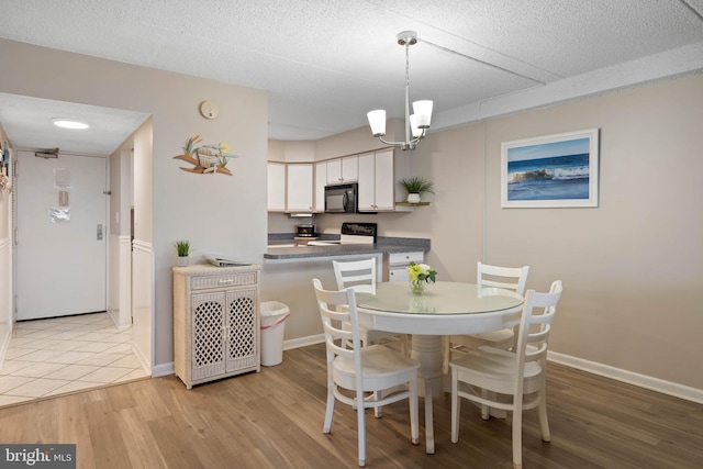 10300 Coastal Hwy Unit 104, Ocean City, MD 21842 - dining room featuring light wood-style floors, a notable chandelier, baseboards, and a textured ceiling