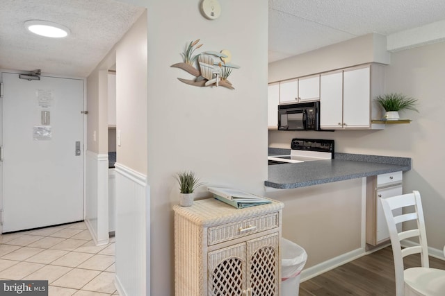 10300 Coastal Hwy Unit 104, Ocean City, MD 21842 - kitchen with black microwave, a textured ceiling, range with electric cooktop, white cabinetry, and dark countertops