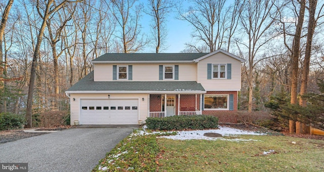 view of property with a garage, covered porch, and a front lawn