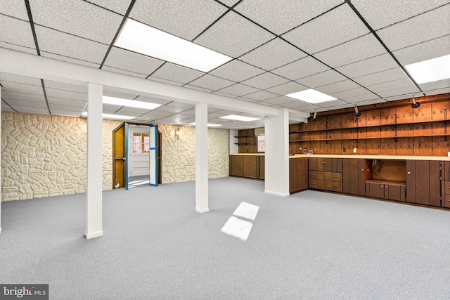 basement featuring a drop ceiling and light colored carpet