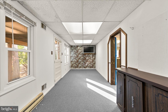 corridor featuring baseboard heating, a paneled ceiling, a healthy amount of sunlight, and carpet