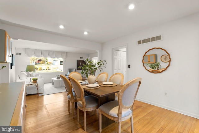 dining space featuring ornate columns and light wood-type flooring