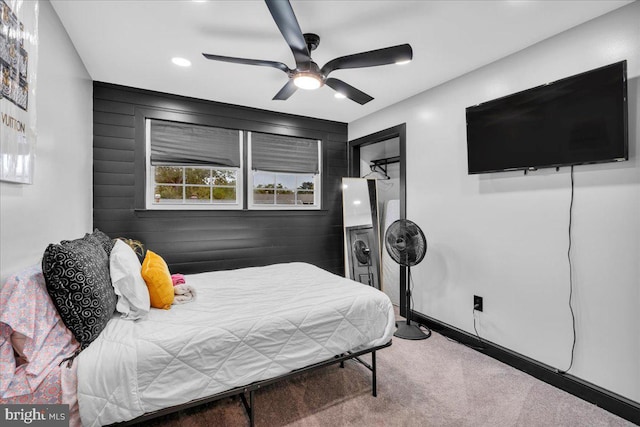 bedroom with wooden walls, ceiling fan, and carpet flooring