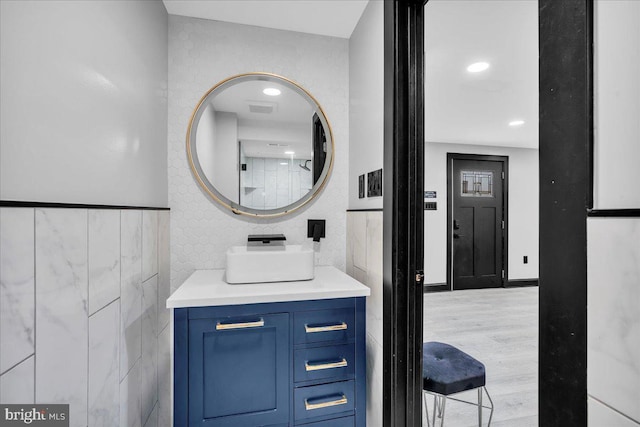 bathroom with tile walls, hardwood / wood-style floors, and vanity