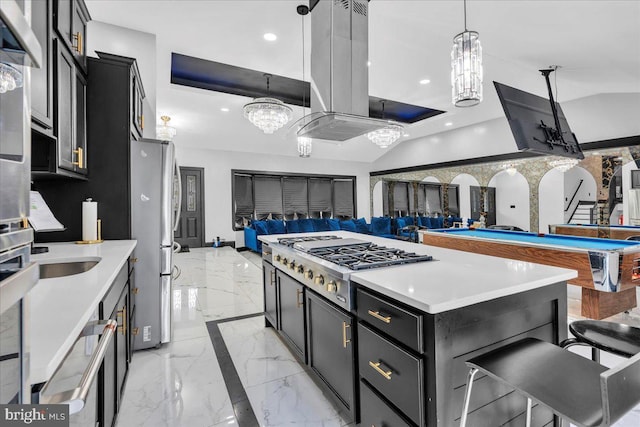 kitchen with island range hood, decorative light fixtures, appliances with stainless steel finishes, a kitchen breakfast bar, and a kitchen island