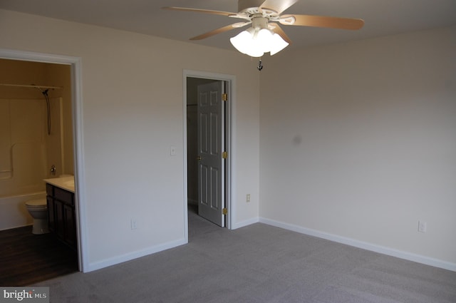 unfurnished bedroom featuring carpet floors, baseboards, a spacious closet, a closet, and ensuite bath