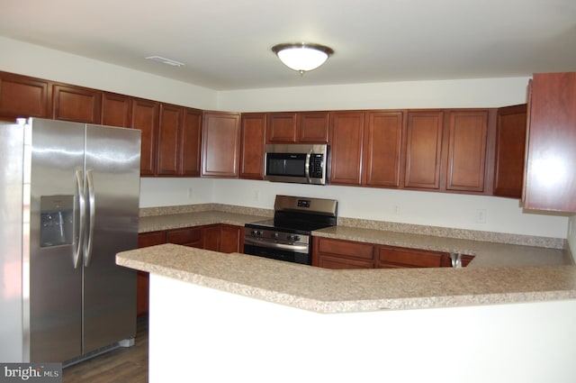 kitchen featuring a peninsula, dark wood-style flooring, stainless steel appliances, and light countertops