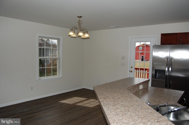 kitchen with hanging light fixtures, dark wood-type flooring, a sink, stainless steel fridge, and baseboards