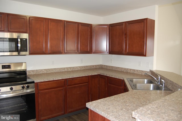 kitchen with stainless steel appliances, light countertops, a sink, and a peninsula