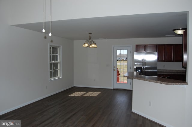 kitchen featuring dark countertops, dark wood-style flooring, stainless steel fridge, and baseboards