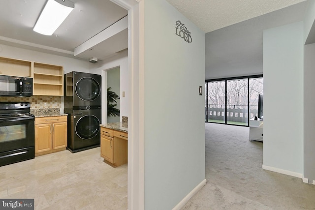 kitchen featuring stacked washer and dryer, tasteful backsplash, light colored carpet, light stone countertops, and black appliances