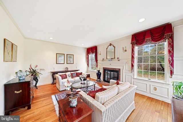 living room with a brick fireplace, crown molding, and light hardwood / wood-style floors