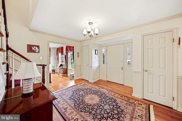 entrance foyer with light hardwood / wood-style floors, a chandelier, and crown molding