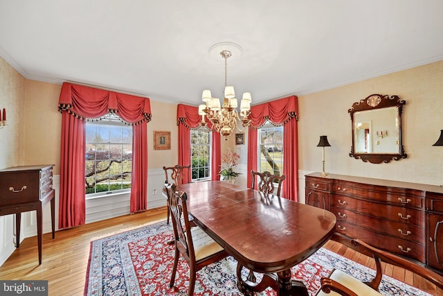 dining area featuring light wood-type flooring, ornamental molding, and an inviting chandelier