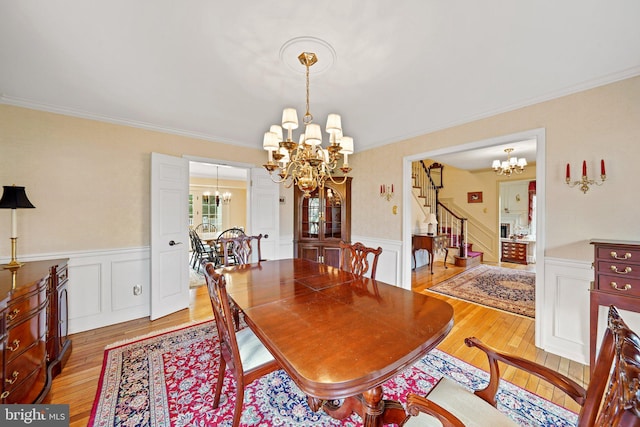 dining room featuring light wood-type flooring, ornamental molding, and a chandelier