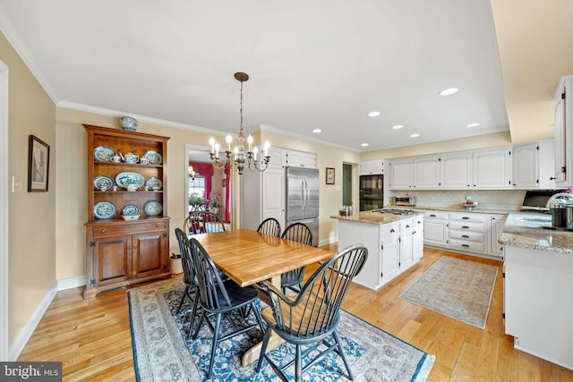 dining area with ornamental molding, light hardwood / wood-style flooring, sink, and an inviting chandelier