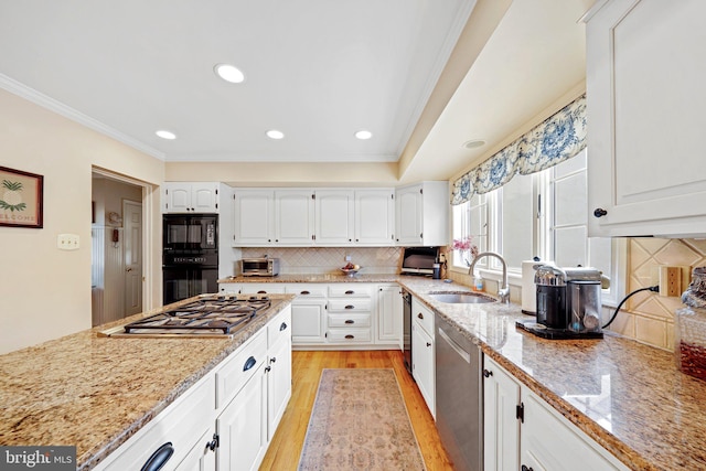 kitchen featuring sink, light wood-type flooring, white cabinetry, black appliances, and light stone countertops