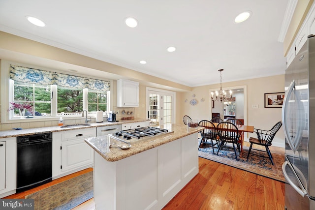 kitchen featuring appliances with stainless steel finishes, white cabinetry, hanging light fixtures, and a center island