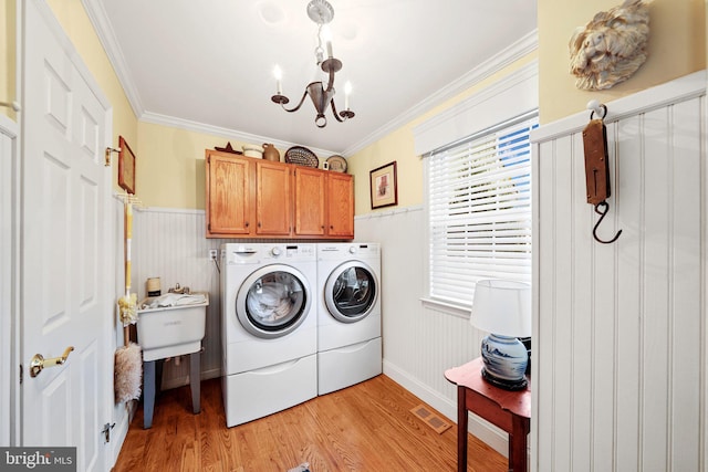 laundry area with light hardwood / wood-style flooring, a notable chandelier, separate washer and dryer, cabinets, and crown molding