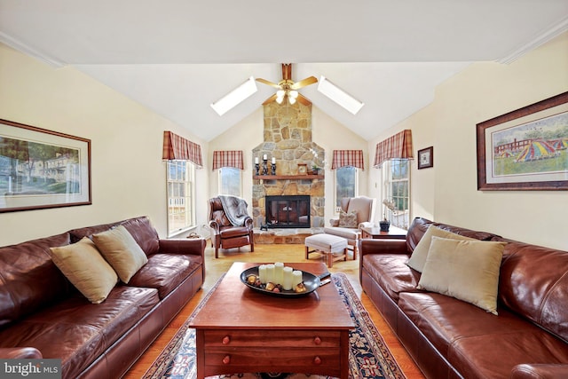 living room with hardwood / wood-style floors, ceiling fan, a stone fireplace, and lofted ceiling with skylight