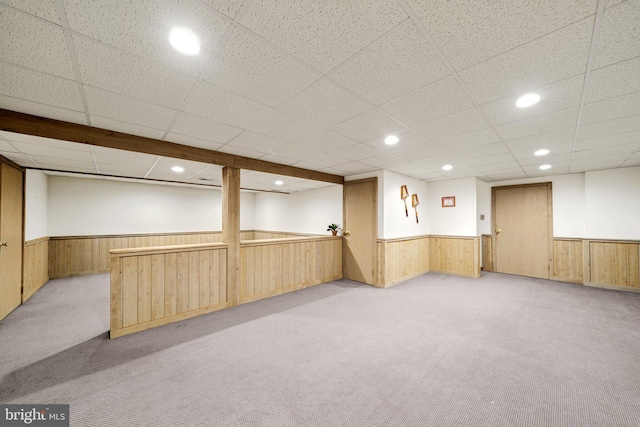 basement featuring wood walls and light colored carpet