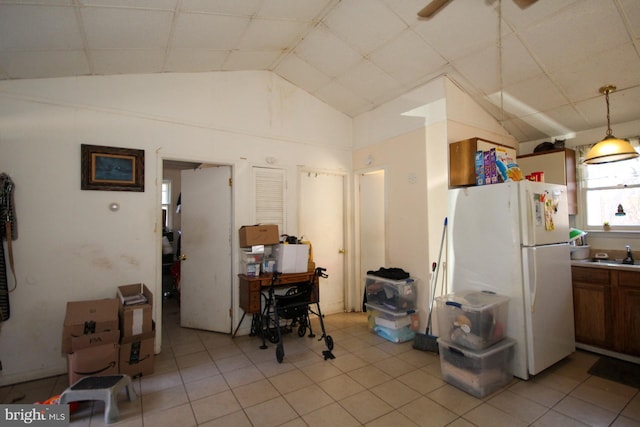 kitchen with pendant lighting, sink, white refrigerator, light tile patterned flooring, and vaulted ceiling