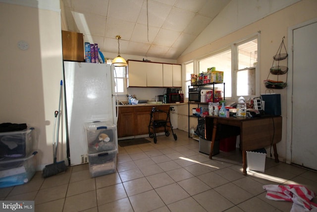 kitchen featuring white refrigerator, lofted ceiling, hanging light fixtures, and light tile patterned floors