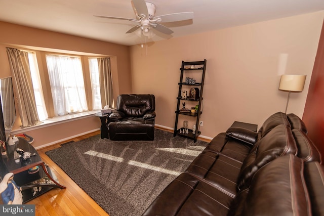 living room featuring a ceiling fan, baseboards, and wood finished floors