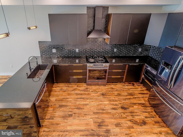 kitchen featuring wall chimney exhaust hood, sink, tasteful backsplash, oven, and light hardwood / wood-style floors