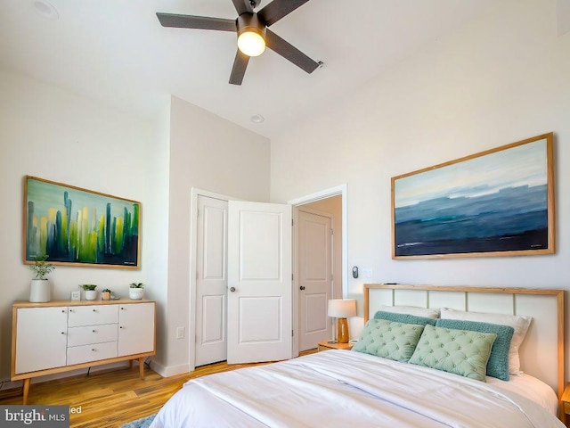 bedroom featuring ceiling fan, lofted ceiling, light wood-type flooring, and a closet