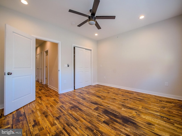 unfurnished bedroom with dark wood-type flooring, ceiling fan, and a closet